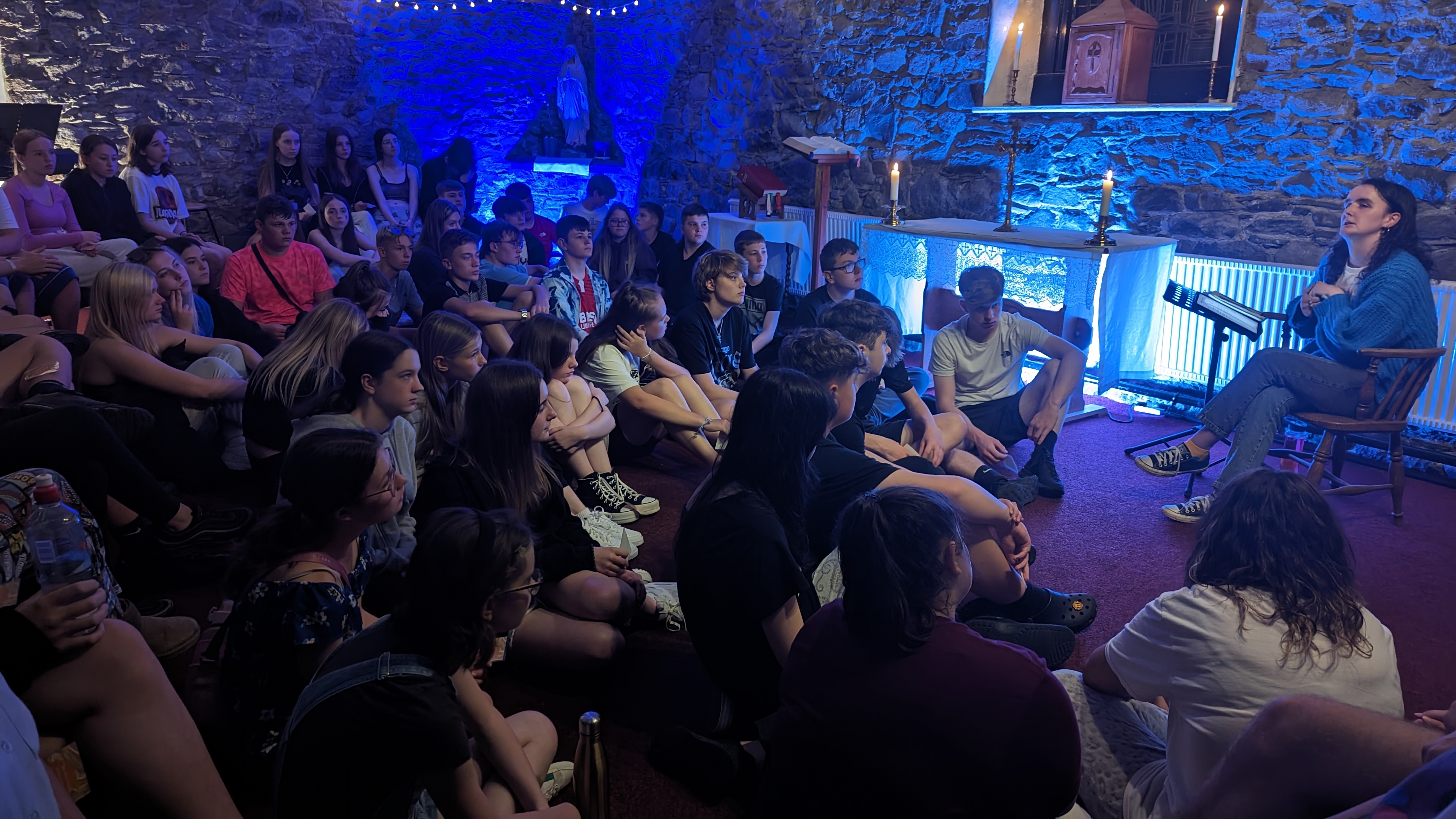 Young people gathered in the candlelit stone chapel