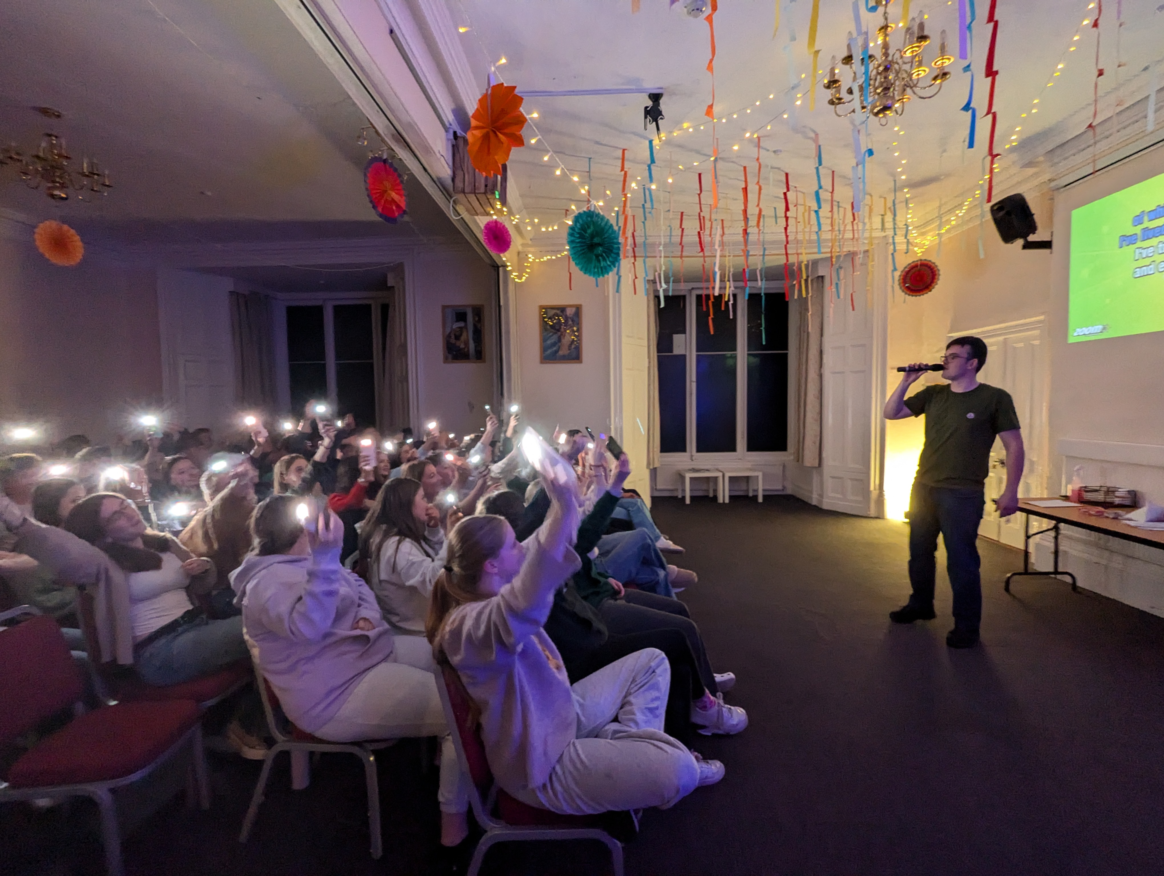 Young people at an evening worship session, phone lights raised